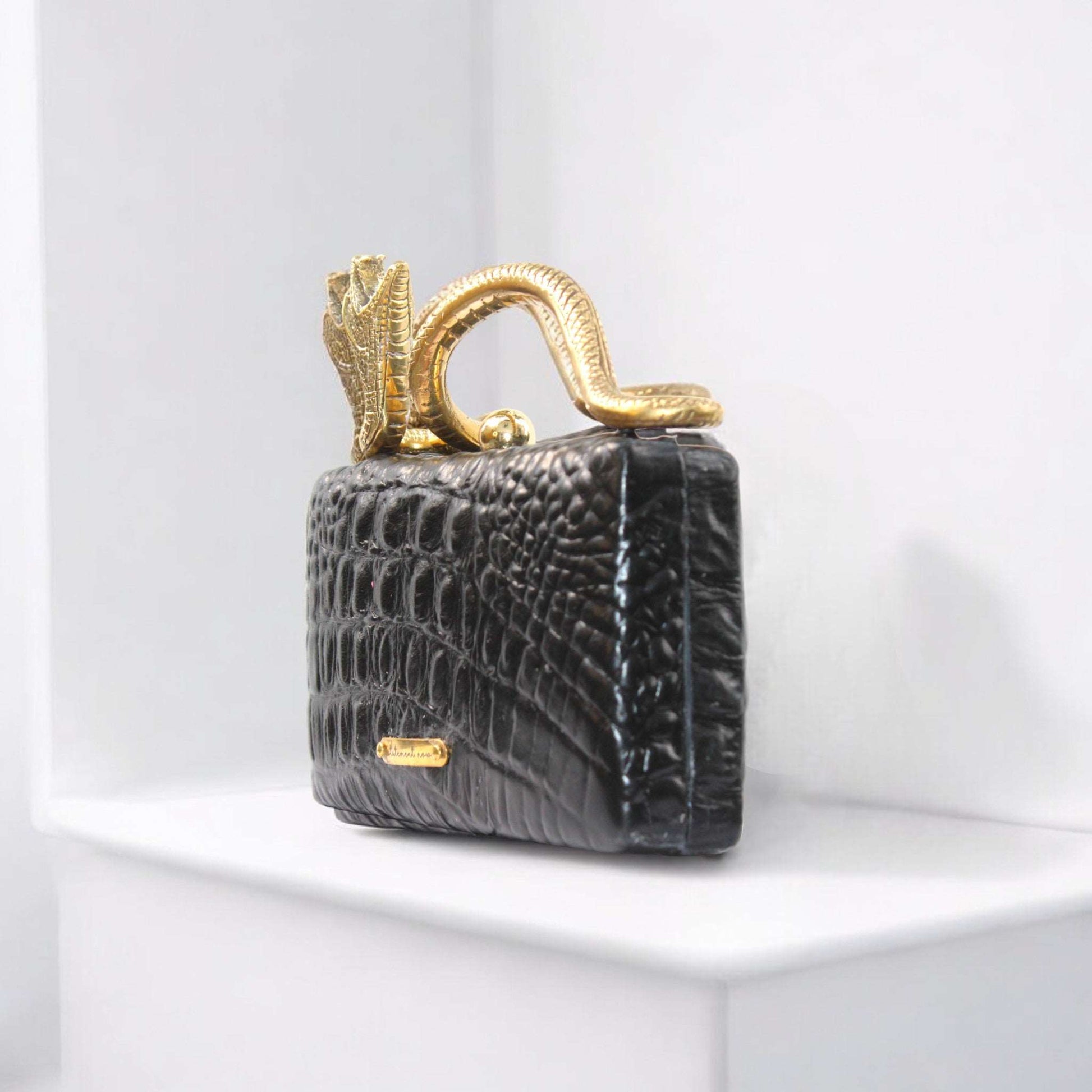  Handcrafted from luxurious Italian lambskin leather, adorned with a striking BLACK ALLIGATOR CROCODILE 3D embossed design, this bag is not just an accessory; it’s a statement. Every detail, from the exquisite resin snake-shaped handle to the elegant gold-tone clip closure, speaks to a level of craftsmanship that is simply unmatched.